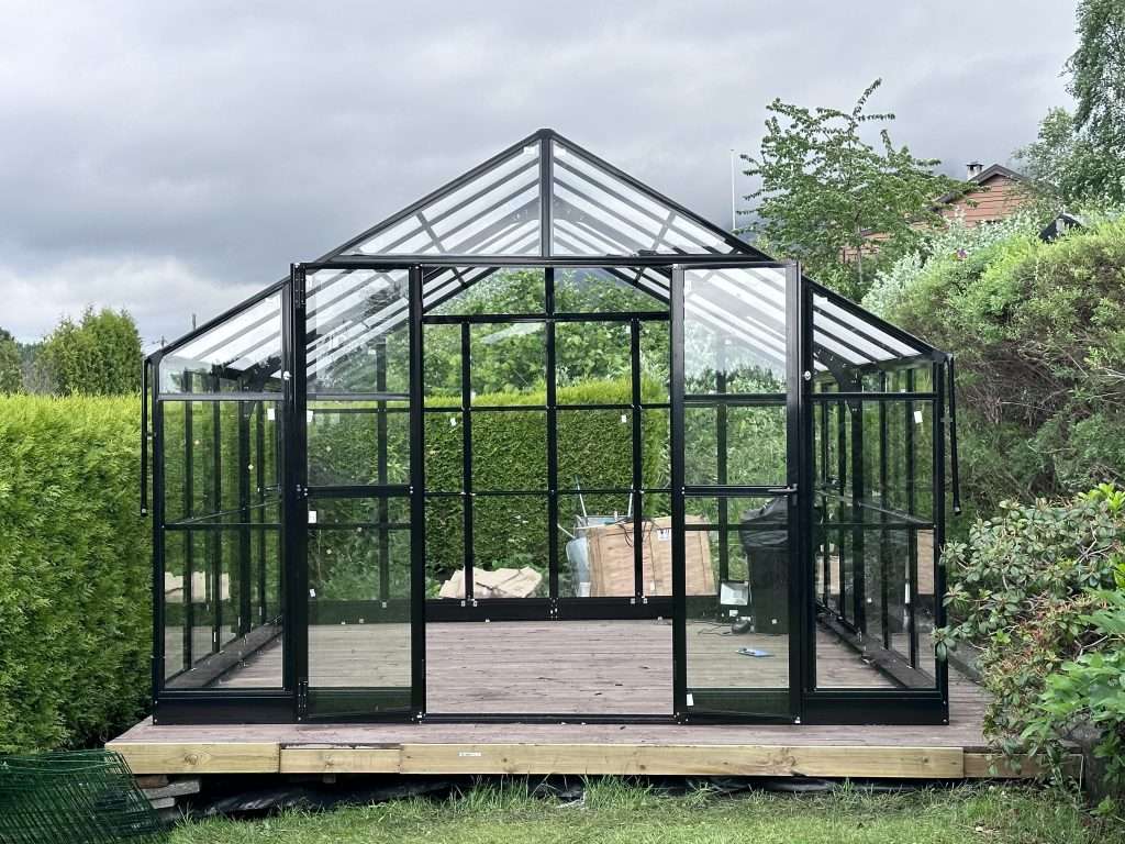 A black greenhouse with a glass door. Greenhouse Haugesund XL 687x354x267 cm Greenhouse Haugesund 552x354x267cm