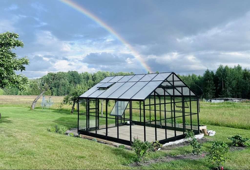 A greenhouse with a rainbow in the sky.