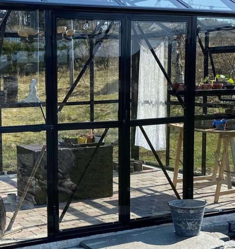 A glass greenhouse with a table and chairs.