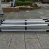 Four aluminum luggage stands on a sidewalk.
