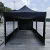 A black tent with white walls and a white canopy.