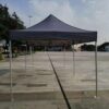 A grey tent sitting on the ground in a park.