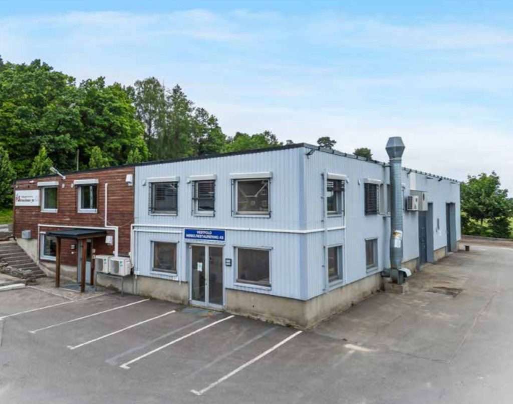 An industrial building with a parking lot and a car.