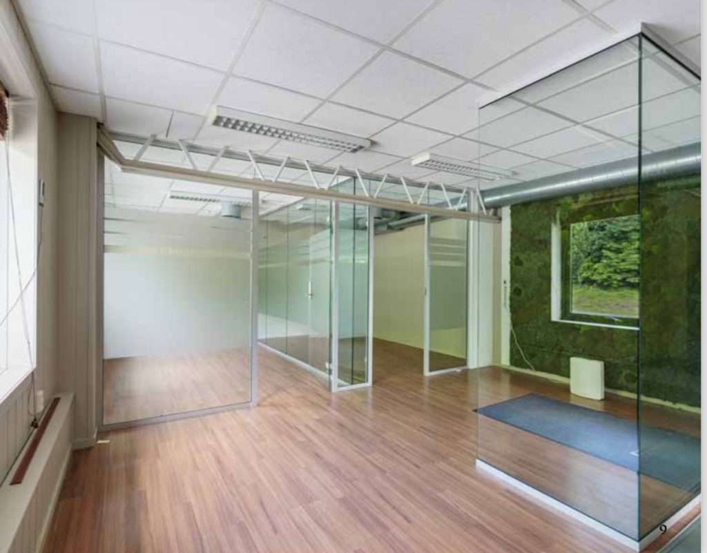 An office with glass walls and wooden floors.