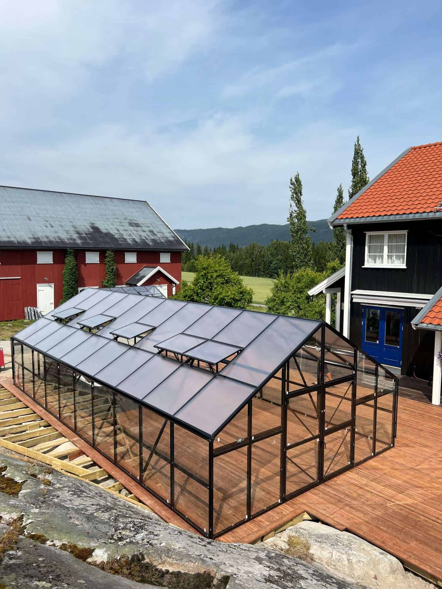 A greenhouse with a roof and a wooden deck.