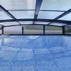 A glass patio cover with an umbrella and chairs.